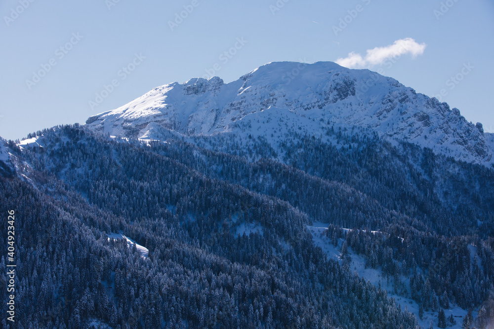 Snow covered mountains, clear blue skies and rocky peaks in the Alps. Winter scene.