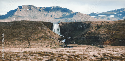 Panoramic view on waterfall in Iceland. stream through a field in Icelandic scenery in green grass with Majestic mount on the background. classic long exposure shot. vintage style