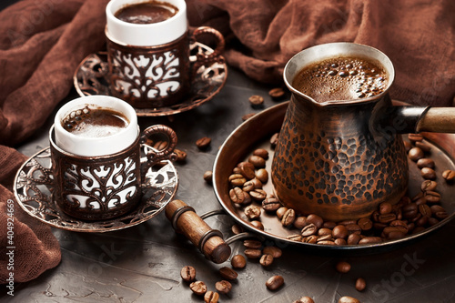 Hot coffee in Turkish copper  pot, traditional mugs  and coffee beens