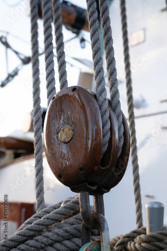 Brown wooden pulley with ropes on a ship. Focus on the wood of the pulley