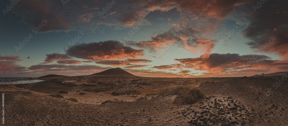 sunset landscape with warm colors where you can see a mountain and clouds panoramic photography