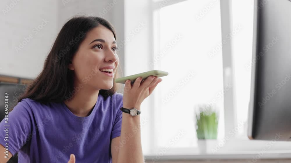 Close up. Relax office worker. Attractive brunette woman using smartphone voice recognition. Beautiful smiling girl recording voice recognition message on speakerphone. Work from home. Close up. Relax office worker. Attractive brunette woman using smartphone voice recognition. Beautiful smiling girl recording voice recognition message on speakerphone. Work from home.