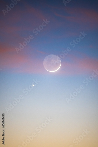Crescent moon and Venus during sunrise with pastel colours and clouds