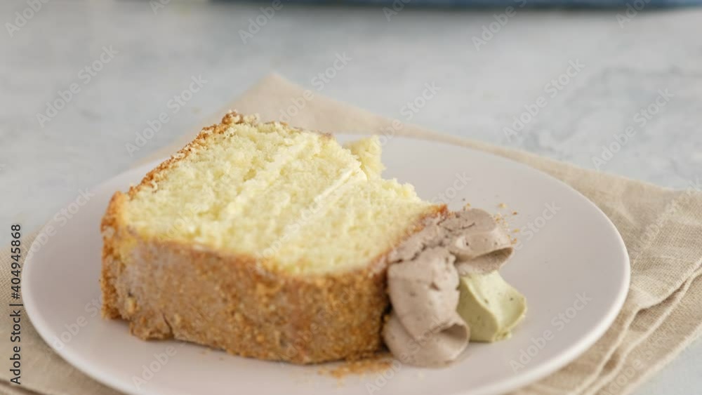 Foreground. Female hands break off a piece of sponge cake with chocolate cream lying on a plate with a dessert fork. Culinary, baking concept. Creamy sponge cake with charlotte cream. Foreground. Female hands break off a piece of sponge cake with chocolate cream lying on a plate with a dessert fork. Culinary, baking concept. Creamy sponge cake with charlotte cream.