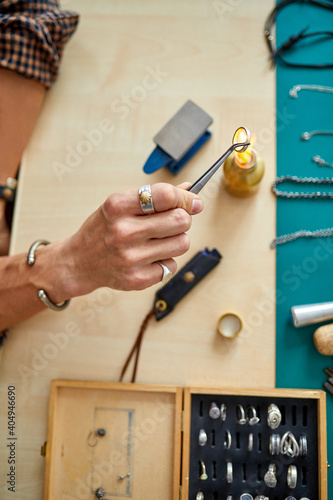 male jeweler using flame torch to solder a ring, making durable jewelry. in workshop. top view