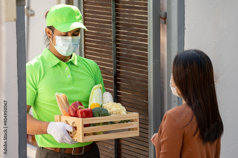 Asian deliver man wearing face mask in green uniform delivering food to customer at home, Door delivery service during covid19. Asian deliver man wearing face mask in green uniform delivering food to customer at home, Door delivery service during covid19.