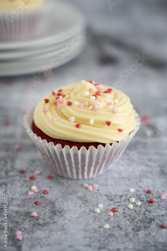 Red velvet cupcake with cream cheese frosting and red and pink sprinkles on top