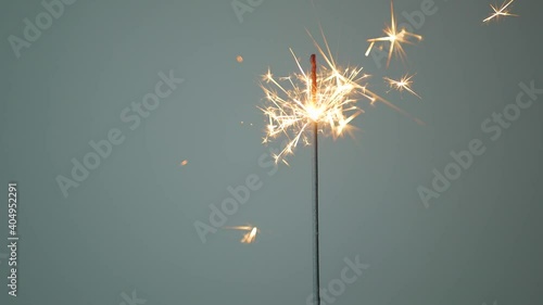 A sparkler burning down on a gray background, static shot. Holiday concept