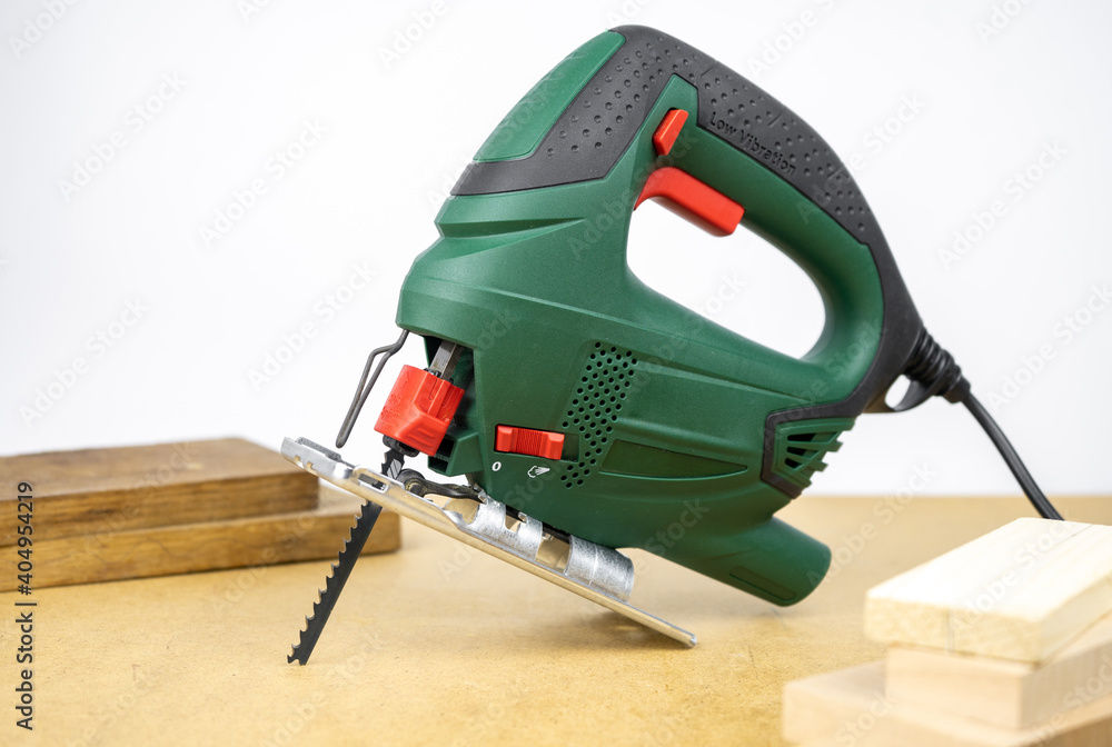 Modern electric jig saw tool for DIY home woodworking. Wood boards on background Modern electric jig saw tool for DIY home woodworking. Wood boards on background