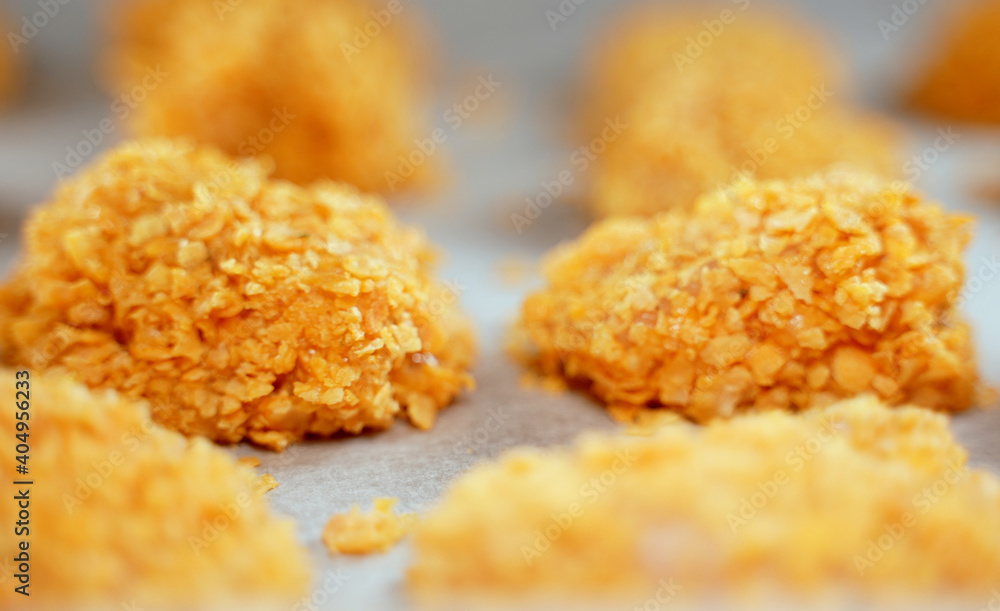 Chicken nuggets on parchment paper before baking. Chicken nuggets on parchment paper before baking.
