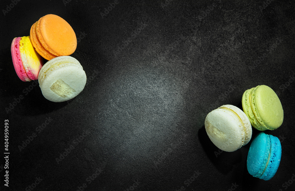 Fotografie Multi-colored bright macarons are laid out on a black background.