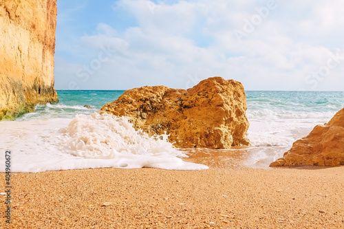 Waves crash on rocks on the sandy shores of benagil beach in portugal