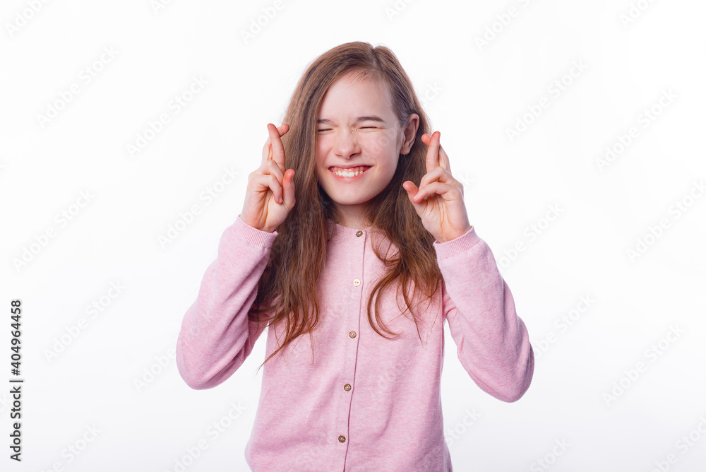 Photo of little girl standing over white background and making a wish with crossed fingers. Photo of little girl standing over white background and making a wish with crossed fingers.