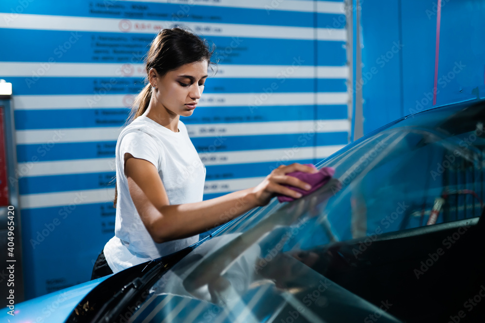 Shot of a young woman cleaning her car Shot of a young woman cleaning her car