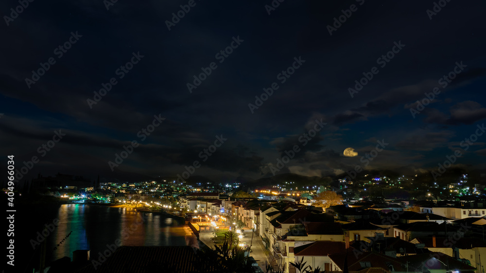 The city of Myrina in Greece, under the cloudy night sky with the full moon