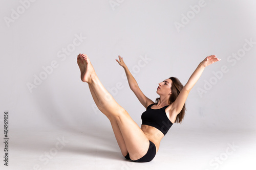 Wallpaper Mural A slender girl in a black sports swimsuit sits doing exercises on a white isolated background. Girl athlete posing on white isolated background with place for text or logo. Torontodigital.ca