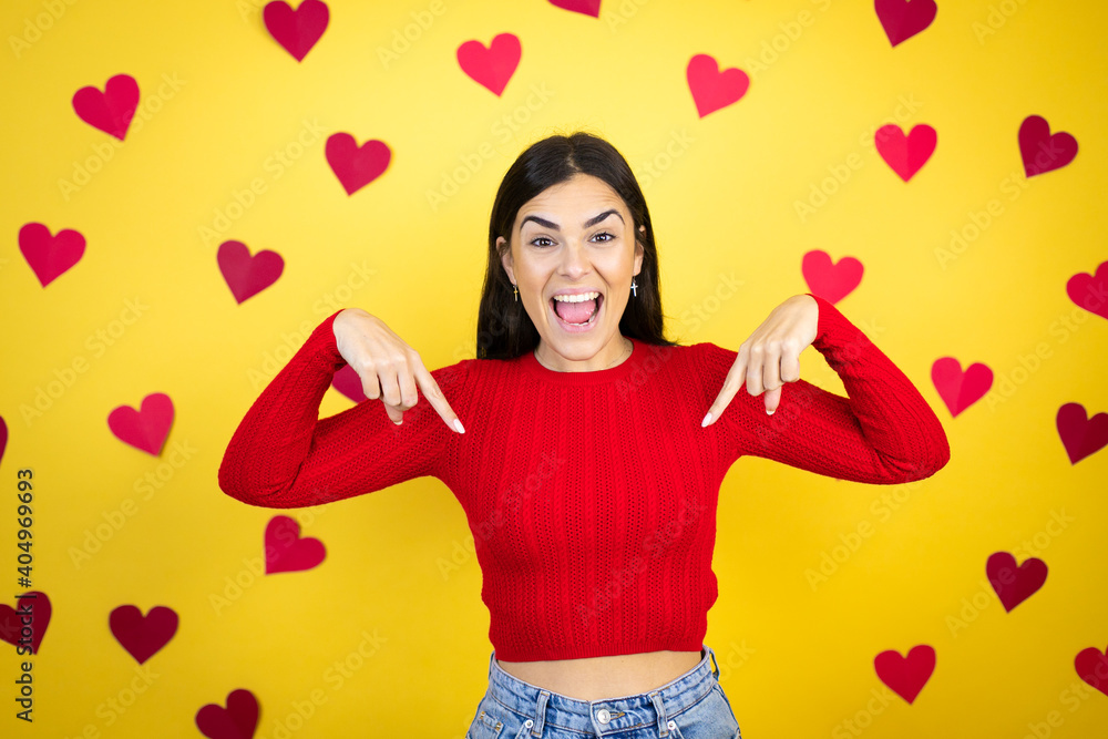 Young caucasian woman over yellow background with red hearts looking confident with smile on face, pointing oneself with fingers proud and happy. Young caucasian woman over yellow background with red hearts looking confident with smile on face, pointing oneself with fingers proud and happy.