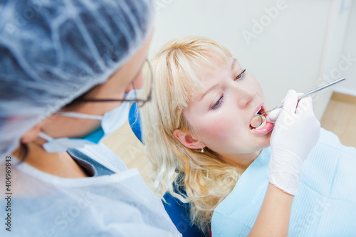 Young Blonde Female patient with open mouth examining dental inspection at dentist office.