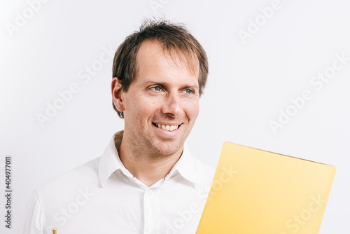 Young man facing forward while holding a yellow folder