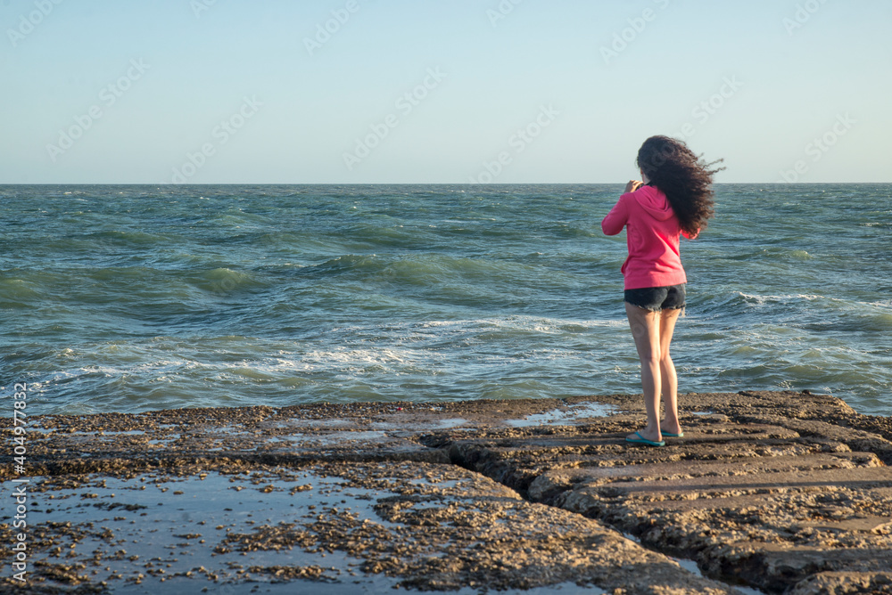 Girl looking at the sea from the coast       