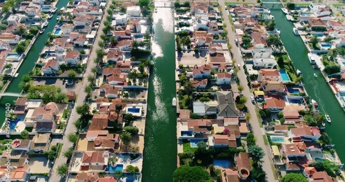 Aerial view over the houses of a Surbubian community. Flying over red roofs in idyllic suburban town with garden and waterway between houses 4K photo