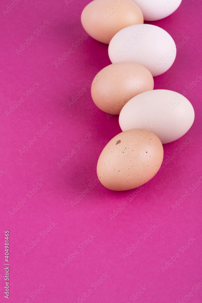 Fototapeta premium Chicken eggs on a pink background. Place for your text. Close-up