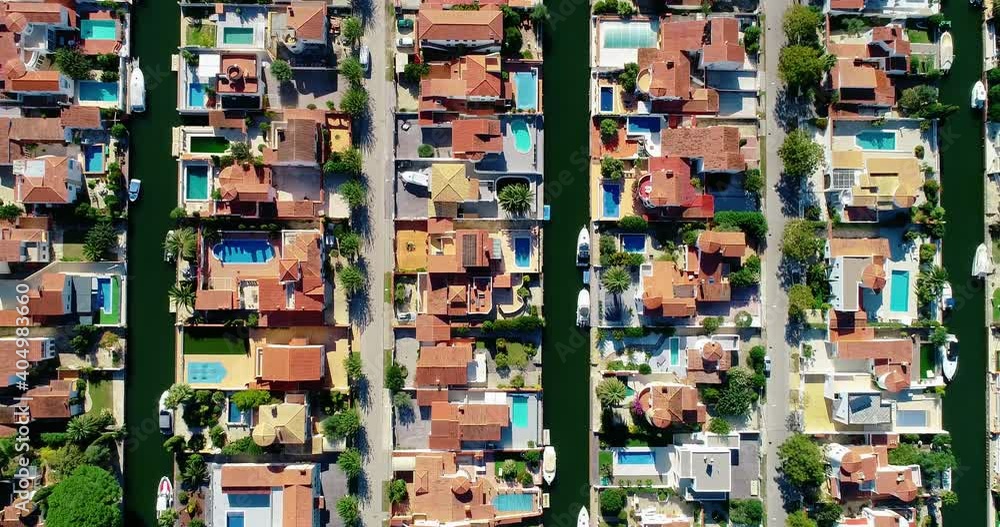 Aerial view above a suburban town in Spain. Red roofs in an idyllic and quiet Surbubian community with garden and waterway between houses 4K Aerial view above a suburban town in Spain. Red roofs in an idyllic and quiet Surbubian community with garden and waterway between houses 4K