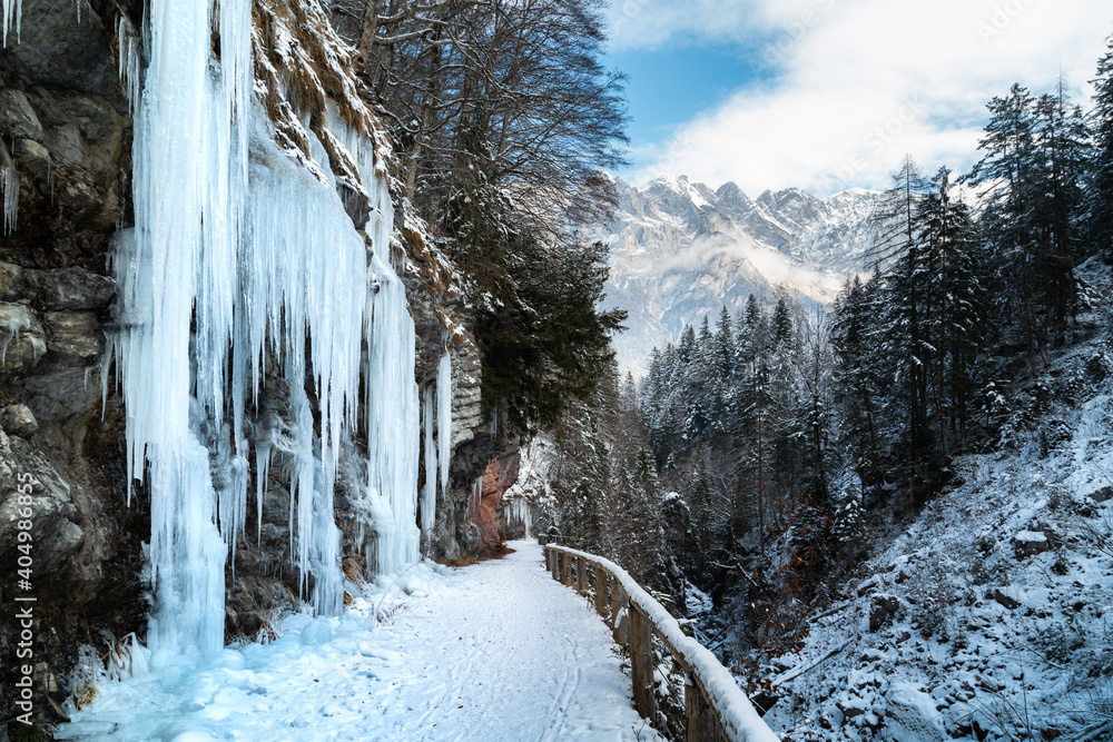Winter wonderland scenery in the Alps with trail and icicles