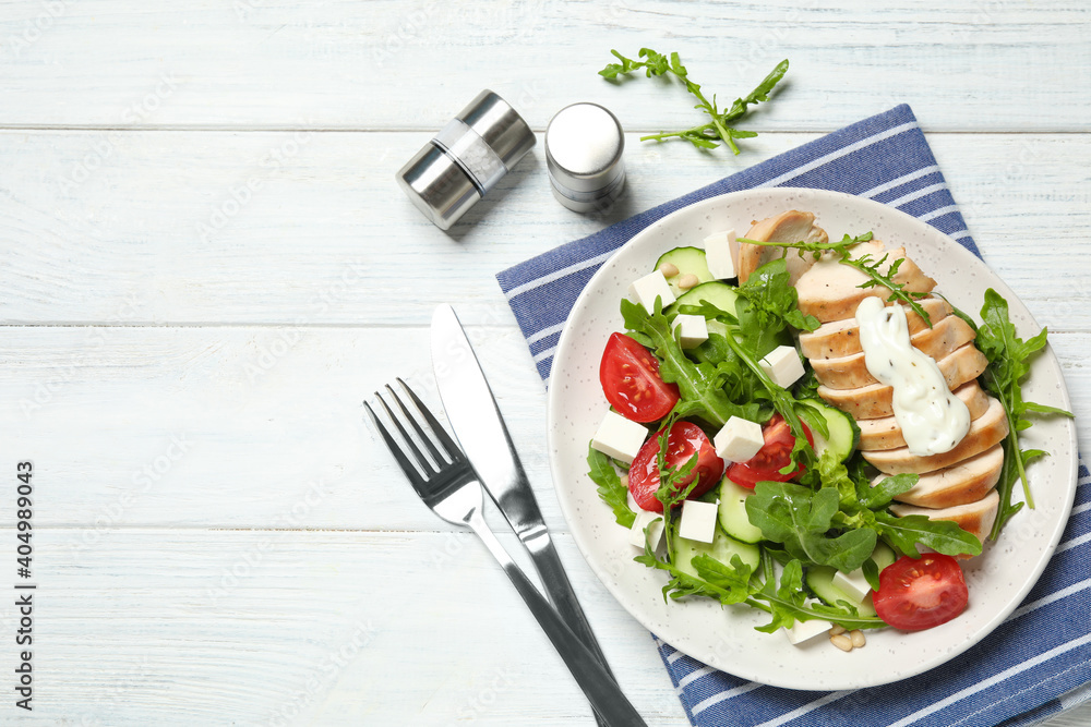 Delicious salad with chicken, arugula and tomatoes on white wooden table, flat lay. Space for text Delicious salad with chicken, arugula and tomatoes on white wooden table, flat lay. Space for text