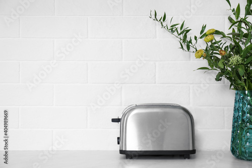 Modern stainless steel toaster on countertop in kitchen. Space for text