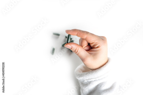 treatment and prevention of diseases, spirulina, capsules with green powder in hand on white