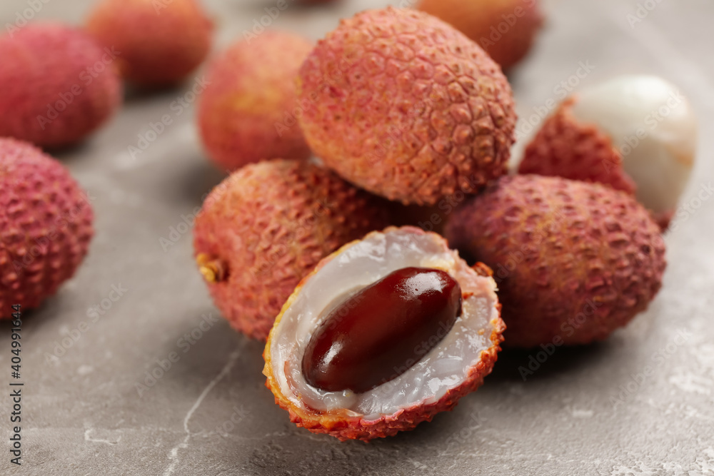 Fresh ripe lychee fruits on grey table, closeup Fresh ripe lychee fruits on grey table, closeup