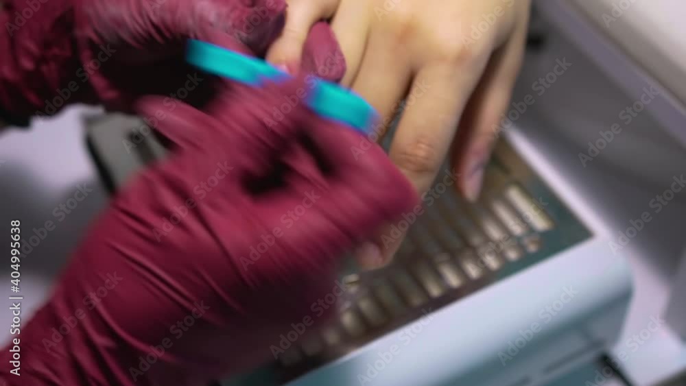 The master of manicure with a blue brush wipes the dust and skin residue from the nails of a client who takes care of himself and came to clean and cover the nails The master of manicure with a blue brush wipes the dust and skin residue from the nails of a client who takes care of himself and came to clean and cover the nails