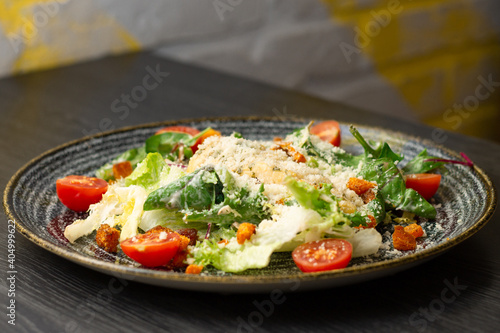 Caesar salad in dark clay plate on wooden table