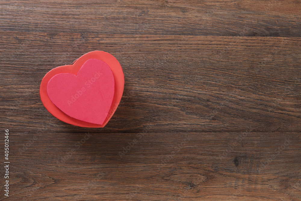 Red heart-shaped gift box on wooden background with space