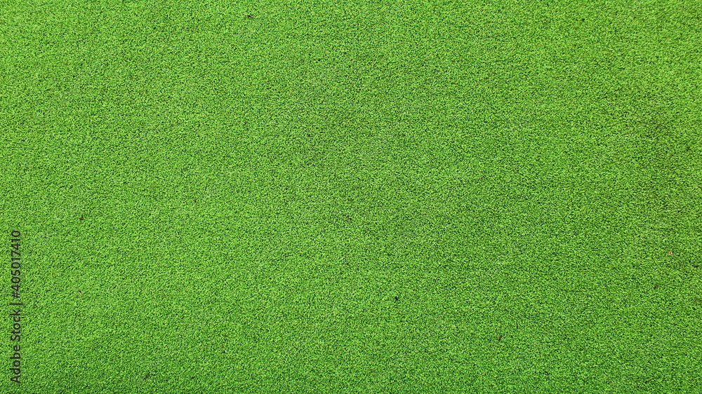 The texture of artificial grass in the field is made of green synthetic plastic