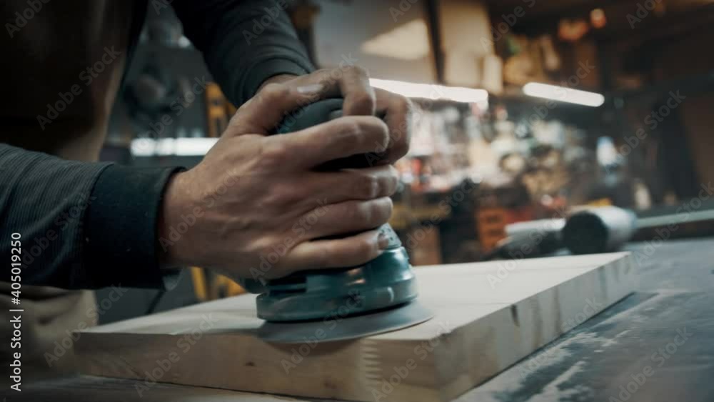 A carpenter grinds a piece of wood for a loft-style chair. Close up. A carpenter grinds a piece of wood for a loft-style chair. Close up.