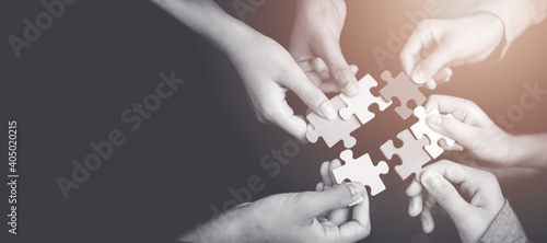 CSR (coporate social responsibility) or teamwork concept.Hands holding jigsaw.Close up top view of young business people putting jigsaw for team together.Charity, volunteer. Unity, team business.