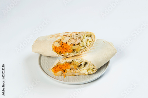 Two parts of Eastern shawarma with layers of chicken meat, cucumber, cabbage, fried potato served on plate, isolated on background. Turkish donner wrapped in lavash bread. Arabic street food. Gyros
 photo