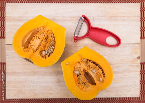 Butternut squash halves and red peeler