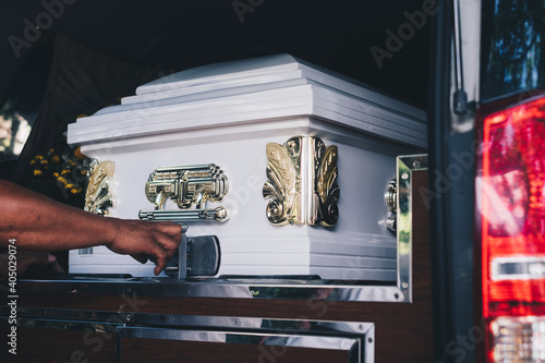 Close up of a casket loaded in a hearse or  funeral plan car or coach for the funeral procession. Selective focus. 