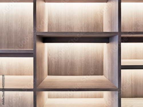 Selective focus image empty wood shelf with LED recess lighting. Built-in interior book shelves. Built-in furniture design component.