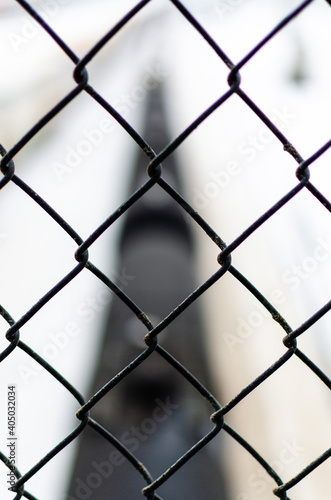 Close up of a chain-link fence with a blurry cargo chain in the background in Winnipeg, Manitoba, Canada