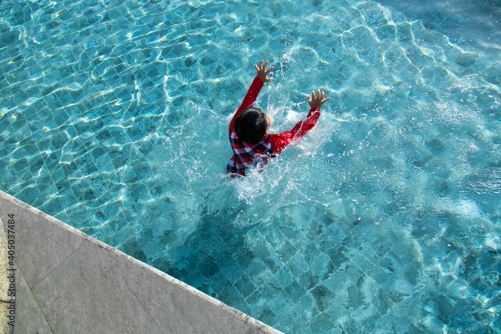 Cute Asian boy jumping into underwater at swimming pool.