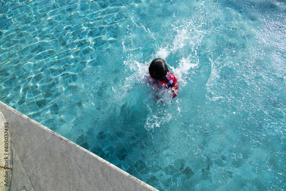 Cute Asian boy jumping into underwater at swimming pool.