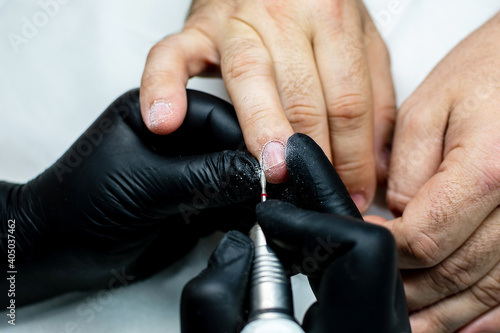 Men s manicure in a beauty salon. Professional manicure for men with a manicure machine. Cosmetologist master cuts and removes the cuticle. close-up.