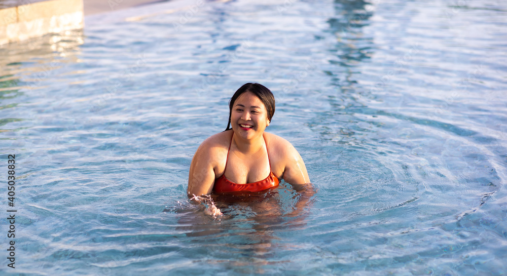 Young beautiful plump woman relaxing in swimming pool at spa resort. Attractive and confident plus size woman.