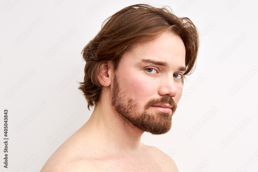 Obraz premium shirtless male with long hair and beard posing at camera, half-naked man looks at camera, calm and serious. isolated white backrgound