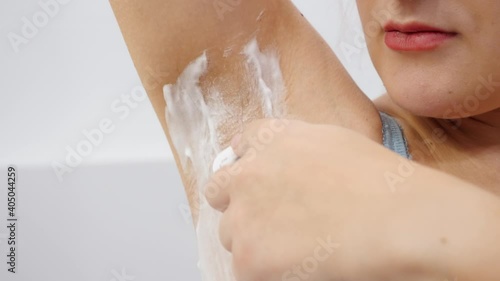 Closeup of yougn woman with growing hair on armpits using razor to remove hair photo