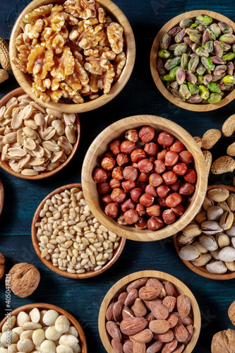 Various nuts, shot from the top in wooden bowls on a dark blue background
